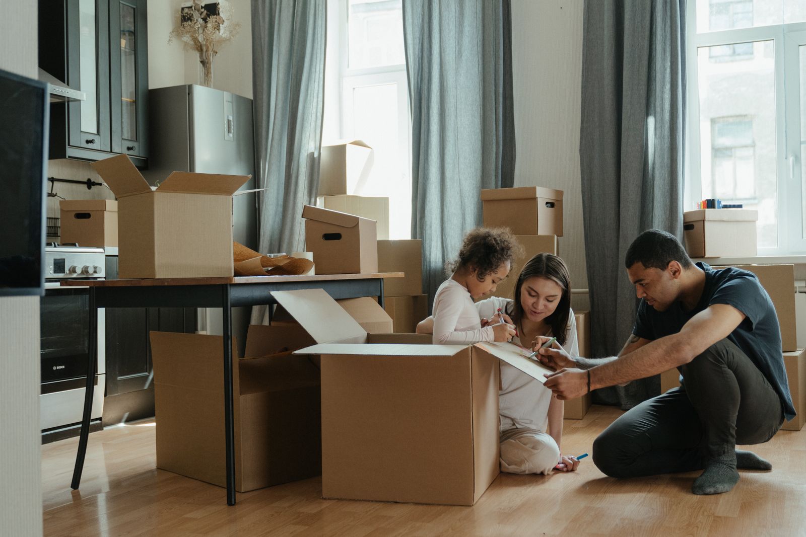 A family unpacking moving boxes in their new St. George kitchen on moving day